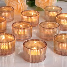 many small glass candles are sitting on a table