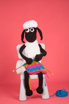 a knitted sheep sitting on top of a white chair