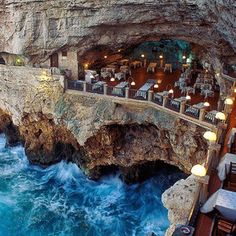 an outdoor dining area next to the ocean with tables and chairs set up on the cliff