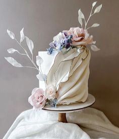 a white cake with pink and blue flowers on it sitting on top of a table