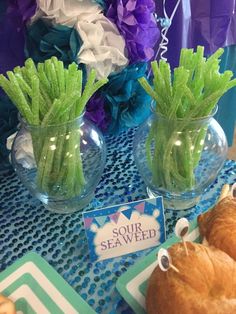 two vases filled with green asparagus on top of a blue table cloth