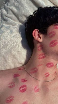 a man laying on top of a bed covered in red lipstick