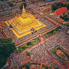 an aerial view of a large crowd gathered in front of a yellow building with many people around it