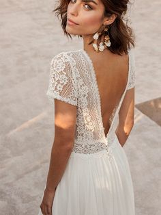 the back of a woman's wedding dress with an open back and lace detailing