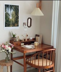 a wooden desk sitting next to a window in a living room under a light fixture