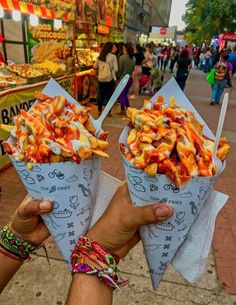 two people holding up paper cones filled with food