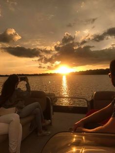 two people sitting on a boat watching the sun go down