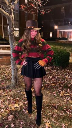 a woman dressed as a scarecrow standing next to a tree