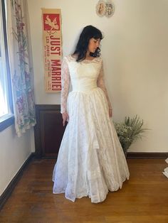 a woman in a white wedding dress standing on a wooden floor next to a window