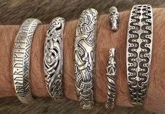 a close up of a person's arm with five different bracelets on it