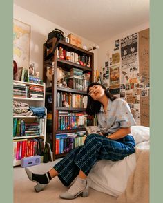 a woman sitting on top of a bed in front of a book shelf filled with books