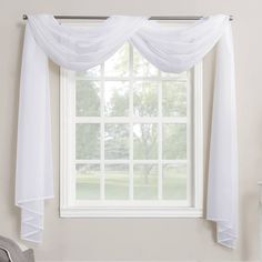 a window with white sheer curtains hanging from it's side