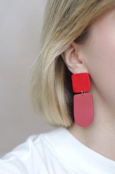 This is a pair of eye-catching statement earrings in a simple, geometric design- the top square is a bright cherry red color and the bottom rounded shape is a faded, dusty red color. These earrings have a minimalist design that is timeless, while the bright duo-tone colors add a modern vibe. These earrings are crafted using polymer clay, a surprisingly lightweight material that won't weigh you down. Each earring is carefully sanded and smoothed to ensure a well-made piece of jewelry that is comf Handmade Rectangular Minimalist Earrings, Handmade Minimalist Rectangular Earrings, Red Minimalist Dangle Earrings, Modern Handmade Rectangular Earrings, Red Jewelry With Matching Earrings For Everyday, Red Drop Earrings For Everyday Wear, Red Everyday Earrings, Trendy Red Jewelry With Matching Earrings, Modern Pink Rectangular Earrings