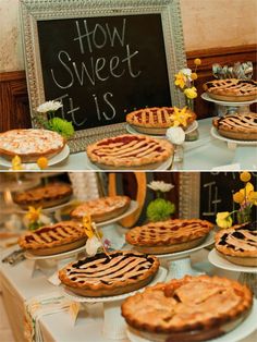 several pies are on display in front of a chalkboard sign and some flowers