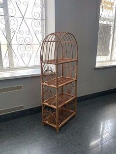 an empty birdcage sits in the corner of a room next to a window