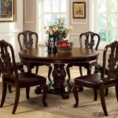 a dining room table and chairs with flowers in vase on the centerpiece, along with an area rug