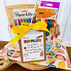 a basket filled with markers, crayons and some writing paper on top of a table