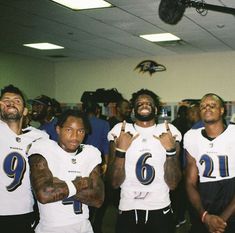 three football players posing for the camera in front of a group of people wearing white uniforms