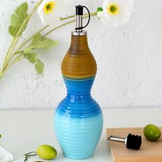 a blue and brown vase sitting on top of a table next to green olives