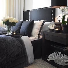 a black and white bedroom with flowers in vases on the nightstand next to the bed