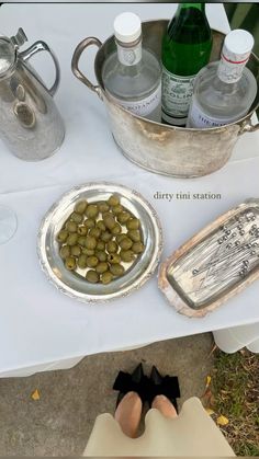 a table topped with plates and bowls filled with olives next to bottles of water