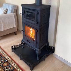 a wood burning stove sitting on top of a hard wood floor next to a bed