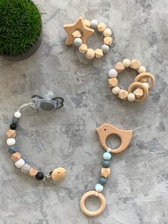 three wooden pacifiers and necklaces sitting on a table next to a potted plant