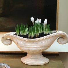 a white vase filled with flowers sitting on top of a table next to a painting