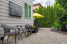 a patio with chairs and an umbrella next to a house