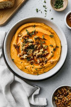 a bowl filled with hummus and nuts next to two bowls of other food on a table