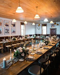 a long table set up with place settings and flowers on it for a formal function