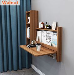 a wooden shelf with books and magazines on it next to a blue curtained window