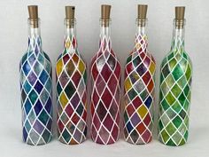 four different colored glass bottles are lined up against a white background, one has a gold cap and the other has a diamond pattern