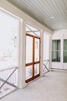 an empty room with two double doors and white paint on the walls, in front of a balcony