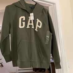 Gap Kids Zippered Hoodie In Moss Green Color With Gap Graphic Is Nice Quality In Size Large Which Fits Ladies Small So Double Duty Measures 18 1/2” Pit To Pit And 22” Length From Collar Brand New With Tags For Boys Or Girls! Gap Hoodie With Letter Print For Fall, Gap Hooded Tops For Fall, Sporty Gap Tops For Winter, Gap Hooded Hoodie With Letter Print, Gap Hoodie With Letter Print, Gap Cotton Hooded Top, Green Fleece Tops, Gap Long Sleeve Tops With Adjustable Hood, Gap Fleece Hooded Tops