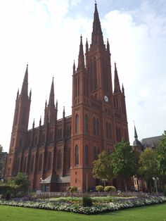 the large cathedral has many spires on it's sides and is surrounded by flowers