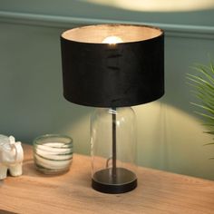 a table with a lamp on top of it next to a glass vase and small elephant figurines