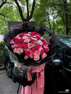 a bouquet of pink roses is being held by a woman in front of a car