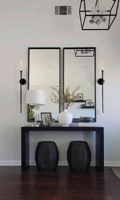 a black table with two mirrors on it and some lights hanging from the ceiling above