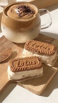 some cookies and ice cream are sitting on a cutting board next to a cup of coffee