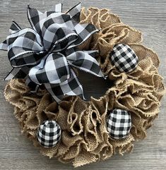 a burlocked wreath with black and white plaid bows on it sitting on a wooden surface