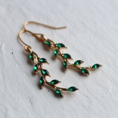 These beautiful earrings feature a curved branch shape with tiny emerald jewelled leaves here and there.  The earrings measure 50mm (two inches) long and are light and comfortable to wear.  When worn, these earrings are designed to hang around the jawline.  The gold metal on the earrings is gold plated brass.  This piece of handmade jewellery comes packaged in a nice recycled gift box with a handmade tag, all ready to give or keep.🖤 FASTER SHIPPING 🖤Need this fast? We offer a Faster Shipping o Cheap Green Leaf-shaped Earrings, Elegant Green Leaf-shaped Earrings, Elegant Green Leaf-shaped Jewelry, Green Leaf-shaped Party Jewelry, Pink Opal Earrings, Branch Tree, Branch Earrings, Silk Purse, May Birthday