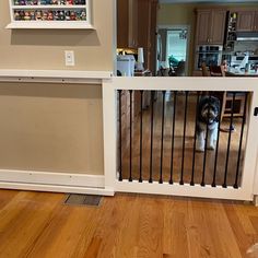 a dog is standing behind a gate in the living room