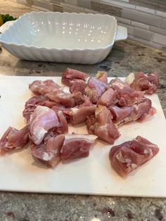 raw meat sitting on top of a cutting board next to a white bowl and knife