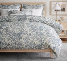 a bed with blue and white comforter in a bedroom next to a night stand