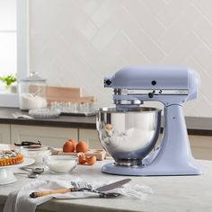 a blue mixer sitting on top of a counter next to other kitchen supplies and utensils