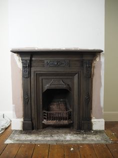 an old fireplace in a room with wood flooring and paint peeling off the walls