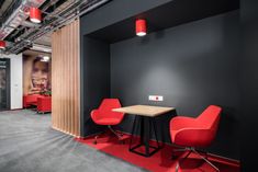 an office with black walls, red chairs and a wooden table in the center of the room