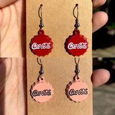 a pair of coca cola bottle caps dangling from earrings