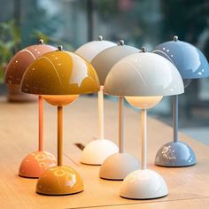 several different colored lamps sitting on top of a wooden table